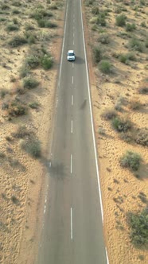 Forward drone shot of car driving on Longewala road through Jaisalmer desert, Rajasthan
