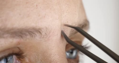 Woman plucking eyebrow hair with tweezers