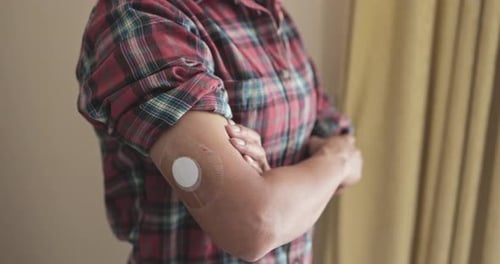 Person Wearing Continuous Glucose Monitor on Arm