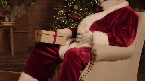 Santa Claus Sitting in Chair with Gift