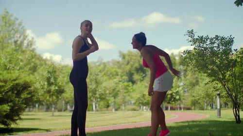 Fitness girls chatting together in the park on a beautiful summer day