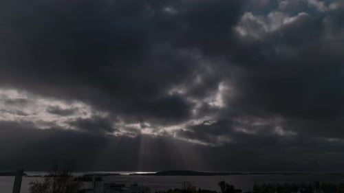 Beautiful time lapse of clouds passing infront of the sun, looking over a calm sea. Sunrays shining
