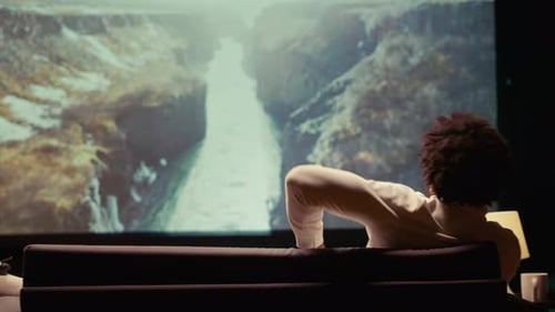 Man Watching Nature Documentary with Breathtaking Cinematography on Huge TV Screen