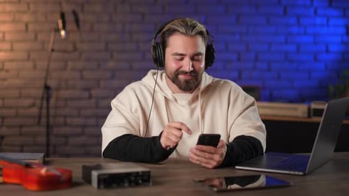 Man in Headphones Using Mobile at Recording Studio