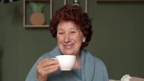 Senior Woman Smiles and Drinks From Cup