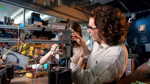 Junger Mann und Frau mit Schutzbrille bei Robotik-Experimenten in einem Labor. Robot und t