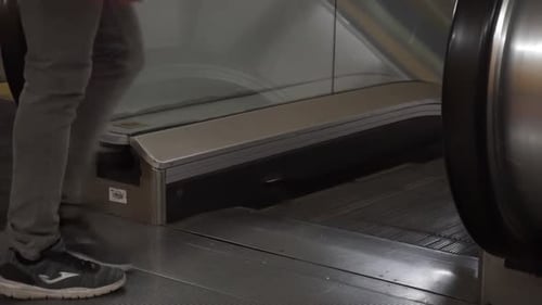 Low angle of man walking on to escalator, lower body only