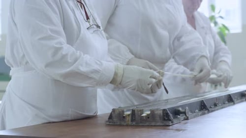 Des travailleurs en gros plan portant des gants marquent les détails de la lame