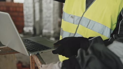 Unrecognizable Construction Workers Using Laptop