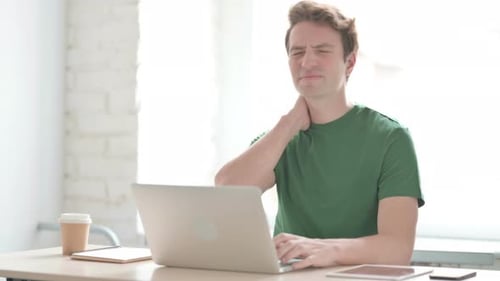 Young Adult Massaging Sore Neck at Desk