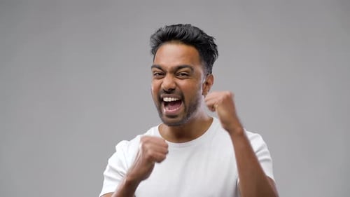 Excited man cheers success in studio close up