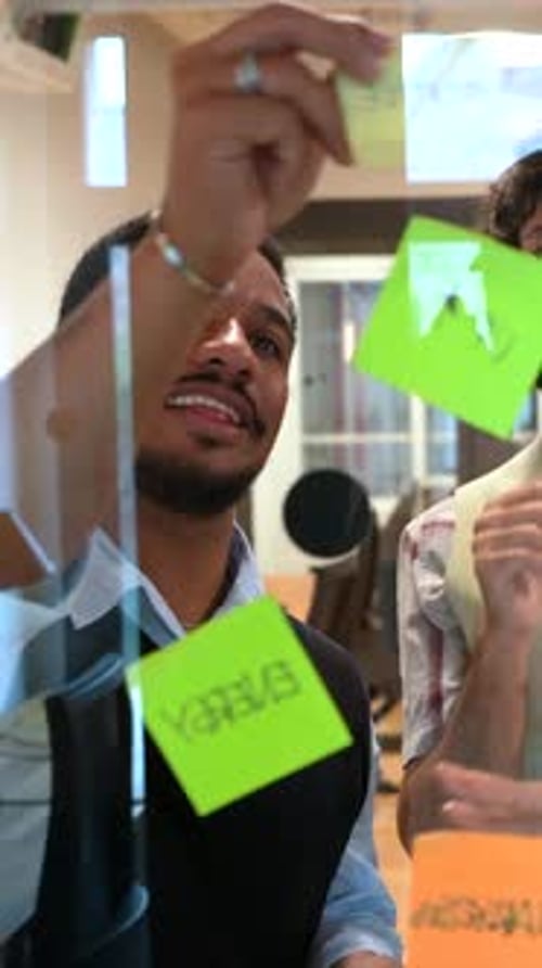 Diverse Coworkers Brainstorming Project with Sticky Notes on Glass