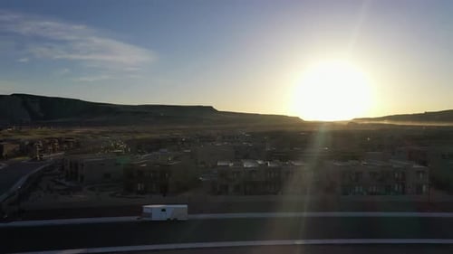 Drone view of urban development houses in a valley surrounded by hills and mountains at sunset