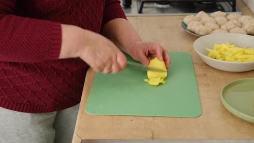 Woman Cutting Potato for Home Cooking in Kitchen