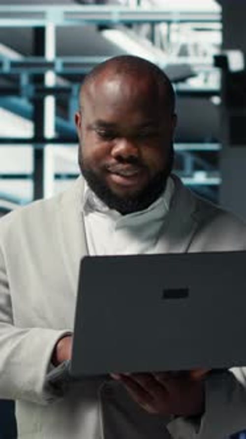 Vertical Video Smiling Engineer in Data Center Managing Software Using Laptop