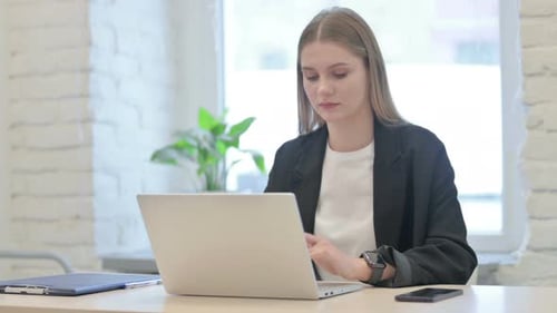 Young Woman Working at Computer Stretches Wrist