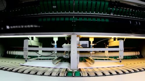 A white sheets folding machine, inside a large industrial laundry.