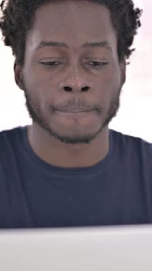Close up of African Man Drinking Coffee while Working on Laptop, vertical video