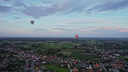 Two hot air balloons flying over a small town