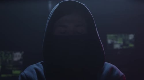 Mysterious Hacker in Hoodie and Mask in Dark Room
