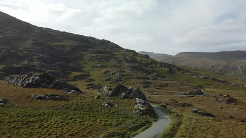 Flying backwards over mountain road and hills in wild Ireland in Autumn