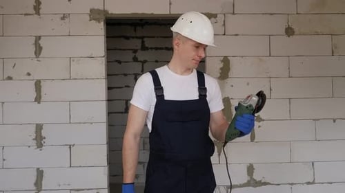 A Smiling Male Construction Worker in a White Helmet with a Working Circular Saw