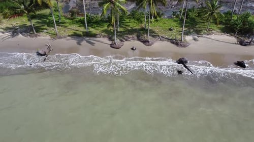 Aerial view of ocean waves rolling onto a beautiful beach with pink sand at sunrise