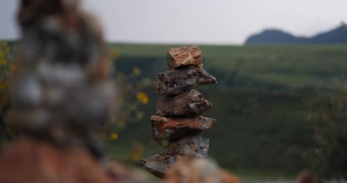 Balanced Stone Cairn on Mountain Viewpoint with Blurred Landscape