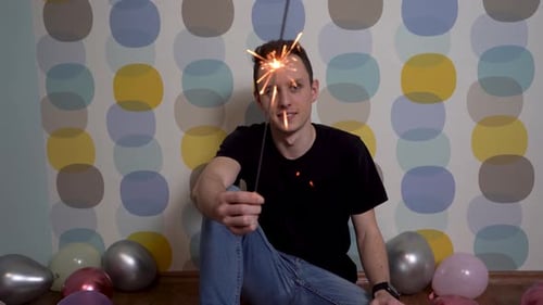 Young Man Celebrates with a Sparkler at Home