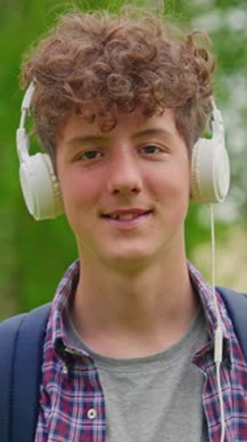 Vertical Video Portrait of Happy Young Curly Teenager with Headphones Outdoor