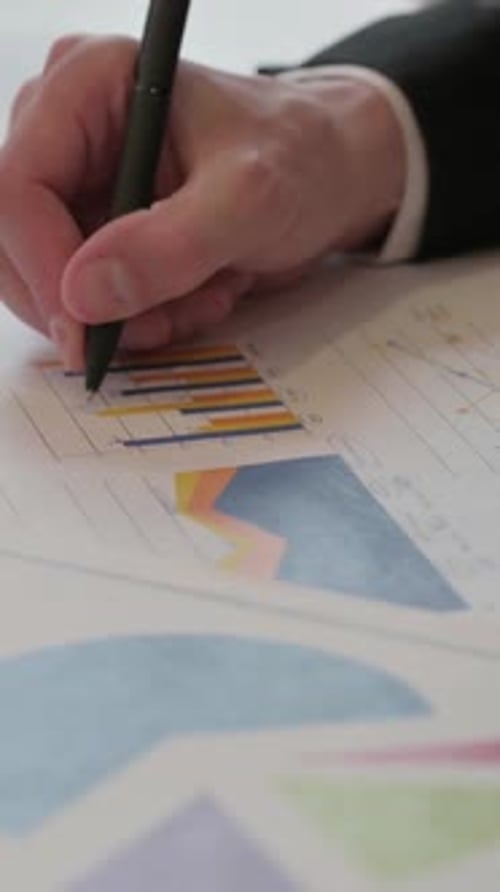 Close up of Middle Aged Businessman Studying Charts while Holding Pen, Vertical Video