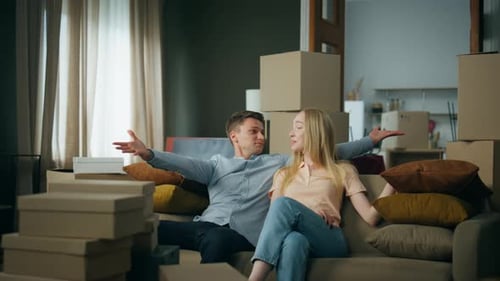 Fröhliches Paar zieht gerne in ein neues Zuhause und sitzt auf einer bequemen Couch.
Jung