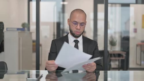 Professional Man Reviews Documents in Bright Office