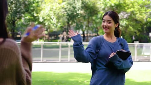 young woman runs to university, carrying a bag. joyfully greets her classmate with a nod and a wave