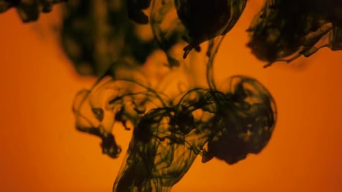 Dark Ink Swirling on an Orange Background