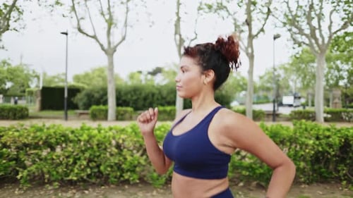 Young sporty woman running in slow motion in a city park