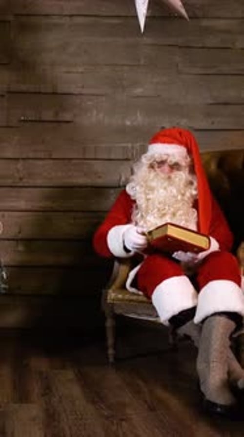 Vertical de Santa Claus sacando un libro de lectura cerca del árbol de Navidad en casa