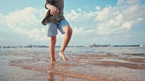 Child Boy Legs Walking Along Ocean Shore on Yellow Sand Beach Summer Vacation