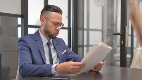 Upset Man Reviews Documents in Office