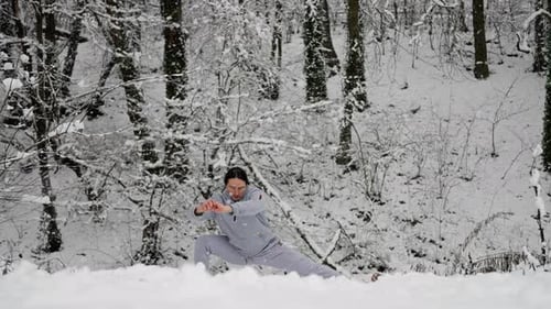 Man Stretching in Snowy Woods During Winter Workout
