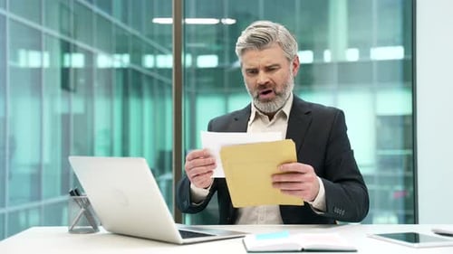 Concerned Mature Man Reads Documents in Office