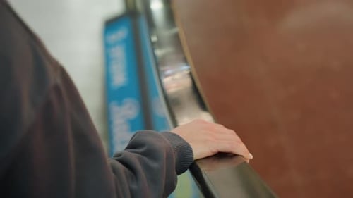 Woman Steps Off Escalator with Hand on Rail in Modern Mall Interior