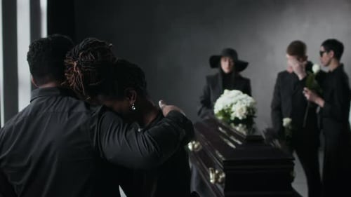 Mourners Gather Around Casket with Flowers