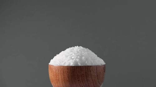 White Table Salt Granules Falling Into a Pile Wood Bowl Gray Color Studio Background Condiment