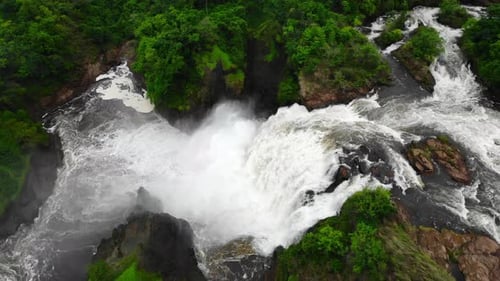 Impressionnante cascade naturelle se déversant dans un bassin rocheux avec des sons rugissants et de la brume s'élevant au-dessus