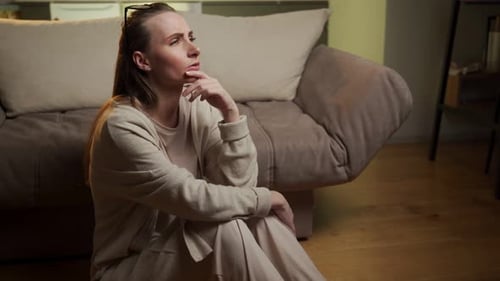 Woman Sitting Sadly on Floor in Living Room