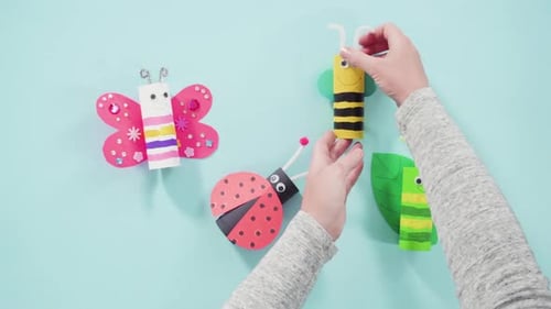 Hands placing paper craft insect art