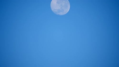 Full Moon Moving Across the Blue Sky