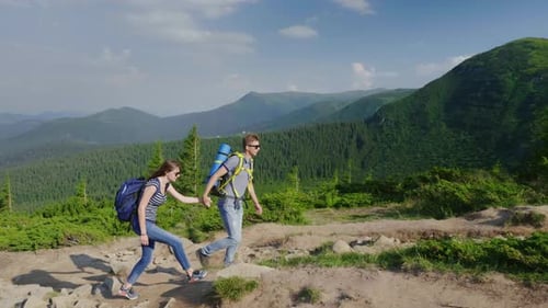 A Man Helps His Woman When Climbing a Mountain Help and Support Concept