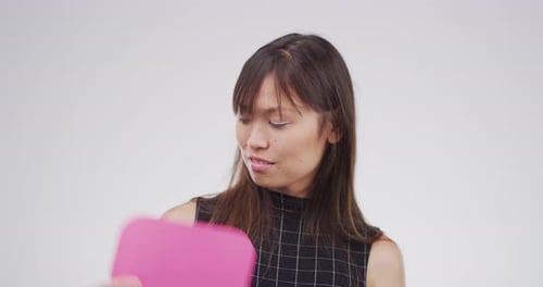 An attractive young woman holding up a speech bubble against a grey background